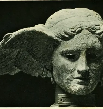 Bronze head of Hypnos with a wing rising from the side and a calm, downcast expression.
