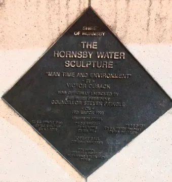 Bronze commemorative plaque for the Hornsby Water Sculpture mounted on a textured wall.