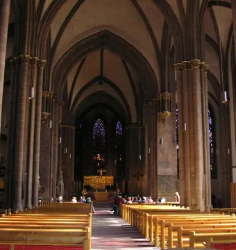 The Mindener Cross, a small golden crucifix, mounted on a tall white candle with a red stripe inside Minden Cathedral.