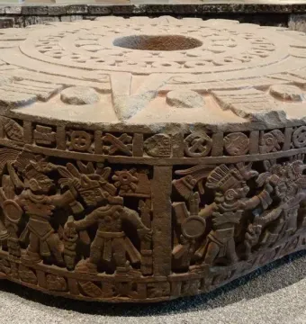 Stone of Motecuhzoma I showing a round carved monolith with concentric patterns on top and figures carved around the sides.