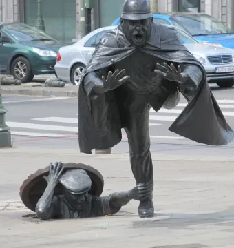 Vaartkapoen bronze sculpture showing a policeman being grabbed by a figure emerging from a manhole.