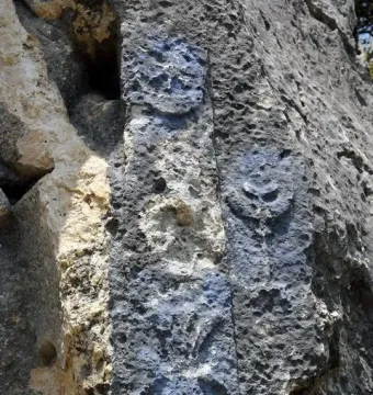 Weathered rock face with ancient carved relief symbols, including circular forms and a radiating star-like motif.
