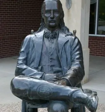 Wild Bill Hickok Memorial statue of a seated man with long hair, a mustache, and a bow tie