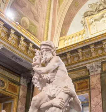 Aeneas, Anchises and Ascanius marble sculpture showing a man carrying an older bearded figure on his shoulders with a child beside them.