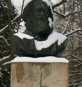 Karl Marx bust on a tall concrete pedestal in a snowy outdoor setting.