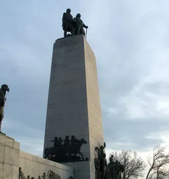 This Is the Place Monument with bronze pioneer statues on top and covered wagon sculptures around the base.