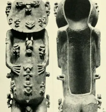 A standing wooden A\'a figure covered with many small carved humanoid figures, with a hollow cavity visible down the back.