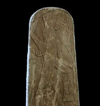 Stele of Baal with Thunderbolt, showing a horned deity raising a weapon above his head, with a small figure below and a plant-like emblem at the side.