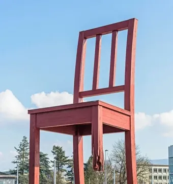 Broken Chair sculpture with a shattered leg towering over people in Geneva.