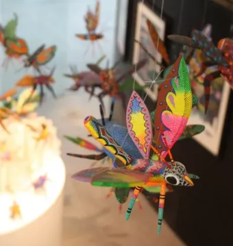 Brightly colored alebrije sculptures resembling insects and fantastical creatures hanging in a display.