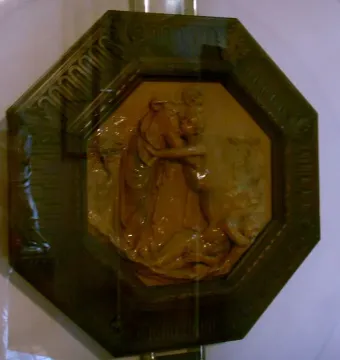 Creation of Eve terracotta relief showing two figures embracing within a dark octagonal frame.