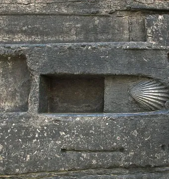 Scallop shell sculpture embedded in a dark gray wall relief at the Monument to Narcís Monturiol.