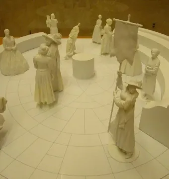 Virginia Women\'s Monument model showing a circular memorial with small statues and a figure holding a tall banner.