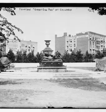 The Great God Pan fountain with a reclining figure and central urn ornament in a grassy area.