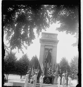 John Paul Jones Memorial with a statue of a uniformed man, surrounded by people in naval dress and flags during a ceremony.