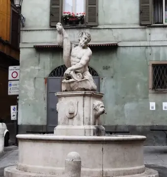 Dolphin Fountain with a stone basin, carved faces, and a seated male figure holding a fish.