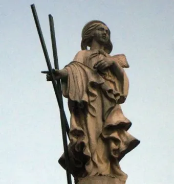 Font de Santa Eulàlia stone statue of a robed female figure holding three staffs and looking upward.