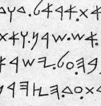 Close-up of the Mesha Stele inscription with dark ancient characters on a light stone surface.