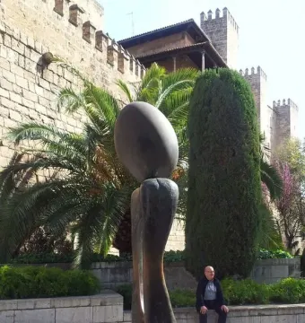Monument a la dona, a dark abstract sculpture with an oval top on a curved base in an outdoor setting.