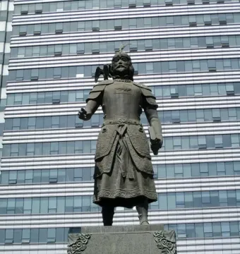 Marco Polo statue in ornate armor with a bird on his shoulder and a book in his hand