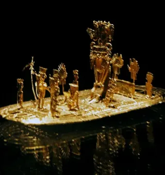 Muisca Raft gold miniature sculpture with small figures on a raft-like base against a black background