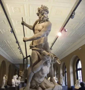 Neptune and Triton marble sculpture with a standing bearded figure holding a staff above a kneeling figure covering their face.