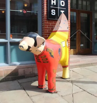 Superlambanana sculpture painted like a red uniform with gold details and a striped banana-shaped tail.