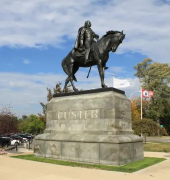The Sighting the Enemy bronze equestrian monument of General Custer on a stone base with CUSTER carved on the front.