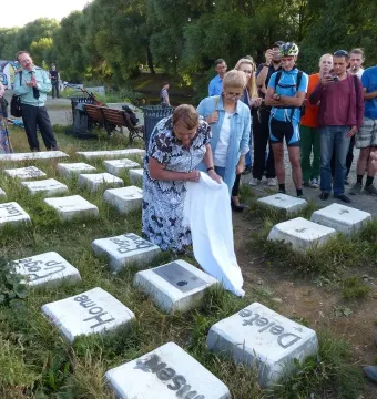 People gather around the Keyboard Monument while a woman unveils part of the installation with a white cloth.