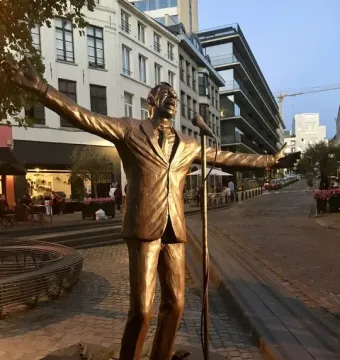 L\'Envol, a metallic statue of Jacques Brel with outstretched arms beside a microphone stand.