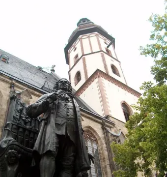 New Bach Monument statue in front of St. Thomas Church with the church tower behind it