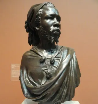 The Nubian Man bronze bust with textured hair, a trimmed beard, and a draped garment.