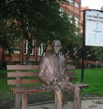 Alan Turing Memorial bronze statue seated on a park bench holding an apple.