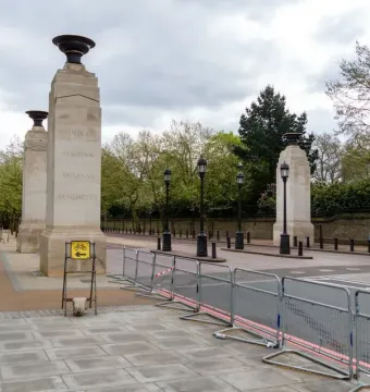 Commonwealth Memorial Gates with four stone pillars and urns along a paved street in London.