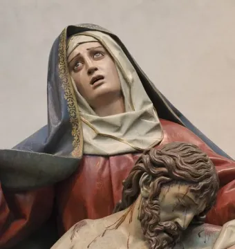 Pietà sculpture showing an anguished woman supporting the lifeless body of a bearded man with a bare torso.