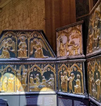 Sant Cugat Casket with ornate gilded panels showing embossed figures and architectural scenes.