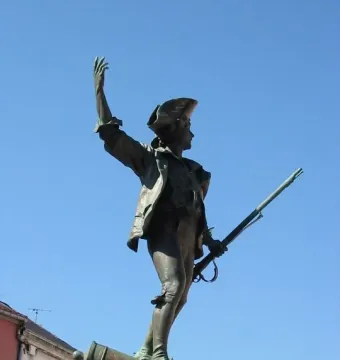 Statue of the Volunteer of 1792, a bronze soldier in a tricorne hat standing on a stone pedestal with one foot on a cannon.