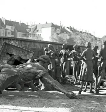 Bronze figures from the Youth Monument arranged among other disassembled statues, with some standing and others lying on the ground.