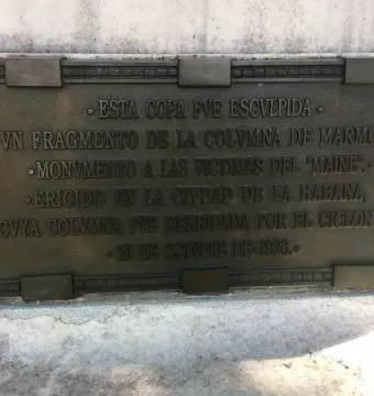 Bronze plaque on the Cuban American Friendship Urn with raised Spanish text and decorative corner details.