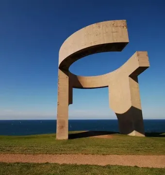 Elogio del Horizonte sculpture on a grassy hill above the ocean