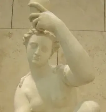 White marble female figure by Giambologna holding a small jug overhead while touching her foot, set on a stone column against a tiled wall.