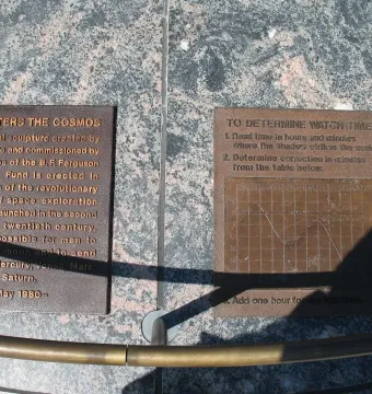 Two bronze explanatory plaques set into dark granite, with strong shadows across the surface.