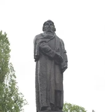 Mickiewicz Monument in Gorzów Wielkopolski, a dark full-length statue on a light tiered pedestal against an overcast sky.