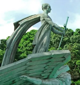 Monumento a Franco showing a green-patinated standing figure holding a staff above another stylized figure with an outstretched arm