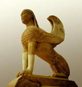 The Sphinx of Naxos stone sculpture with a woman\'s head, feathered wings, and a lion-like body on a decorative base.