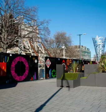 The Chalice sculpture stands in the background on the right, with a tall inverted cone shape and geometric pattern against a blue sky.