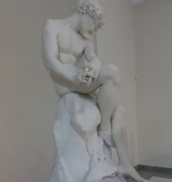 The Exiled, a white marble statue of a seated nude man with bowed head and clasped hands.