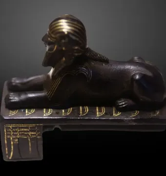 Thutmose III sphinx shown in profile with a gold-striped headdress and beard.