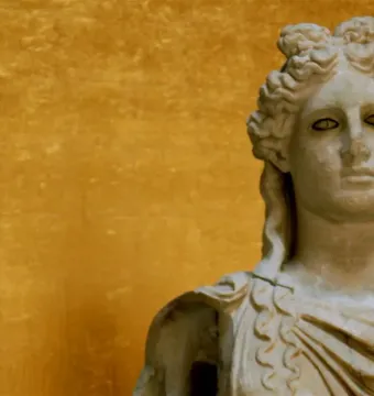 Apollo Barberini marble bust with curly hair and draped shoulders against a golden background.