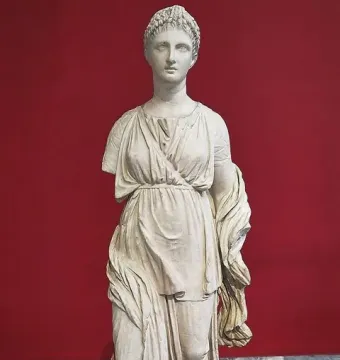Artemis Diadoumena marble statuette with braided hair and draped garments, missing part of the left arm.